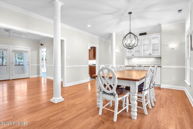 dining space with ceiling fan with notable chandelier, decorative columns, crown molding, and light hardwood / wood-style floors