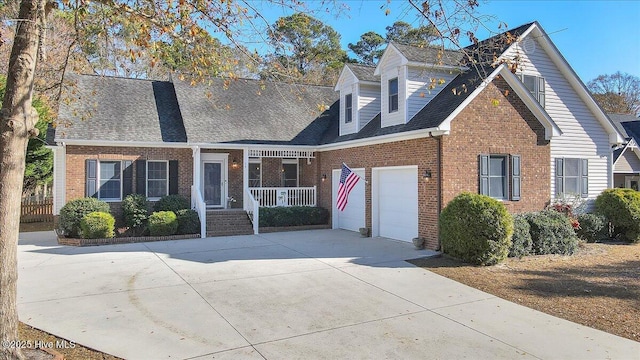 cape cod-style house featuring covered porch and a garage