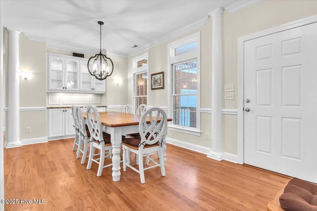 dining area with light hardwood / wood-style floors, plenty of natural light, ornamental molding, and a notable chandelier