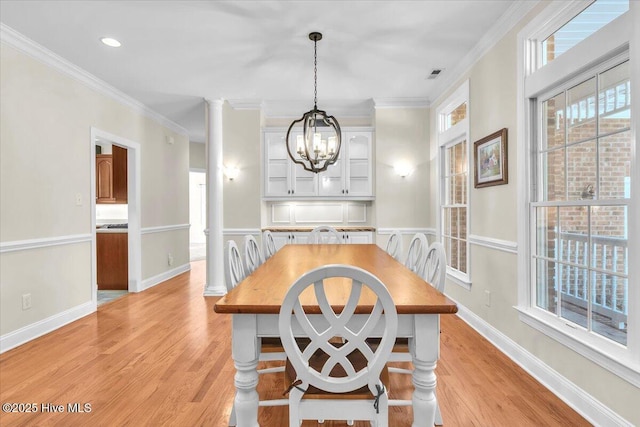 dining area featuring light hardwood / wood-style floors, a wealth of natural light, crown molding, and a notable chandelier