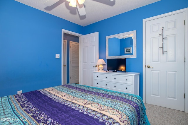 bedroom with ceiling fan, carpet floors, and a textured ceiling