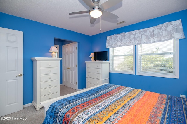 bedroom featuring ceiling fan, light colored carpet, and a textured ceiling