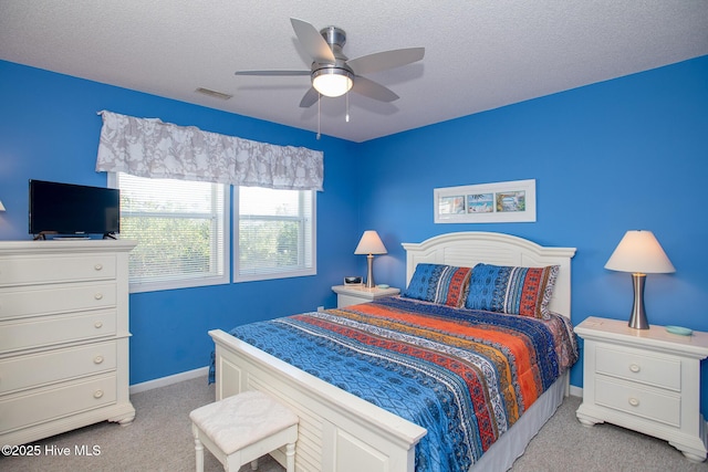 bedroom featuring a textured ceiling, ceiling fan, and light carpet