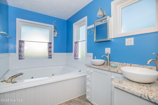 bathroom with vanity, a textured ceiling, hardwood / wood-style flooring, and a tub