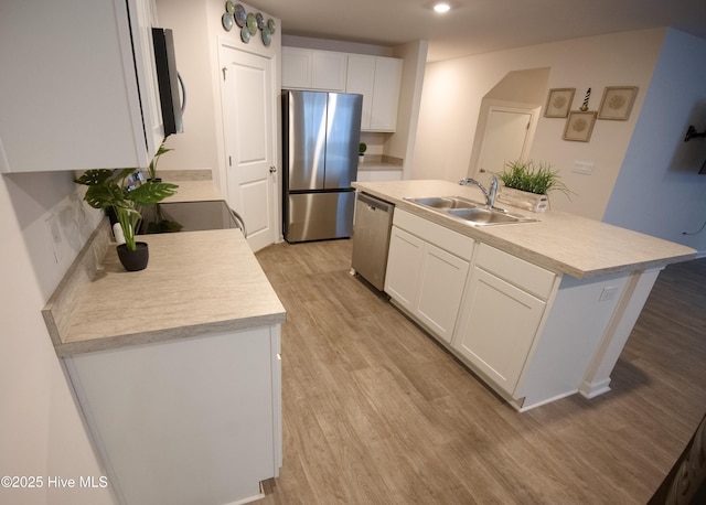 kitchen with a kitchen island with sink, sink, light hardwood / wood-style flooring, appliances with stainless steel finishes, and white cabinetry