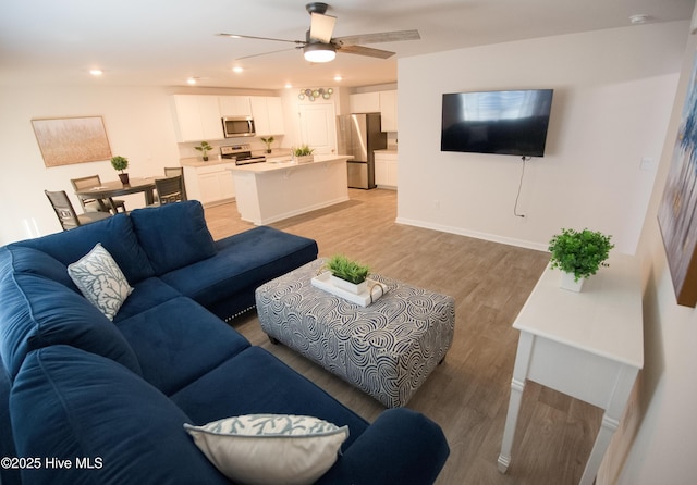 living room with ceiling fan and light hardwood / wood-style flooring