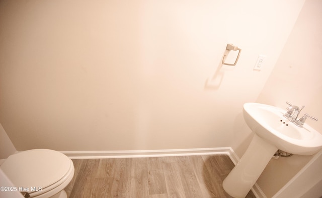 bathroom with toilet, wood-type flooring, and sink