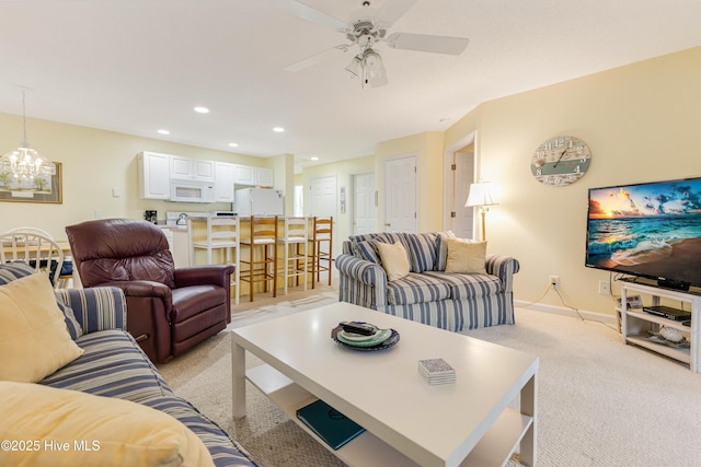 living room featuring ceiling fan with notable chandelier and light colored carpet