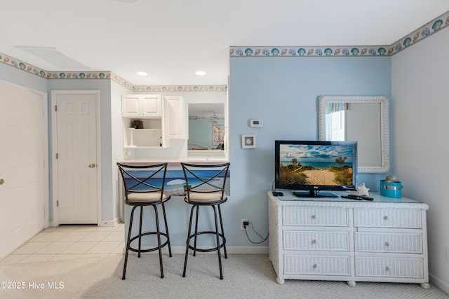 kitchen featuring a kitchen bar, white cabinets, and light tile patterned flooring