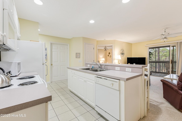 kitchen featuring sink, white cabinets, an island with sink, and white appliances