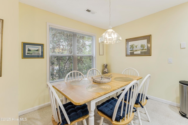 carpeted dining area with a chandelier