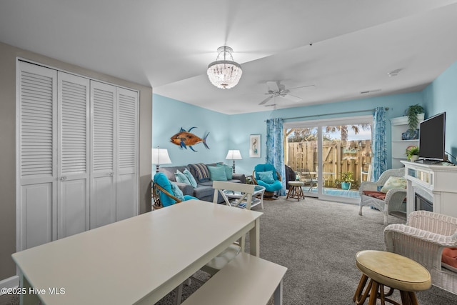 carpeted living room with ceiling fan with notable chandelier