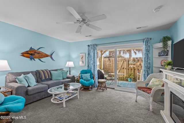 carpeted living room with a premium fireplace and ceiling fan