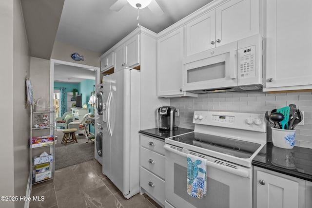 kitchen featuring white appliances, tasteful backsplash, stacked washer and clothes dryer, and white cabinetry