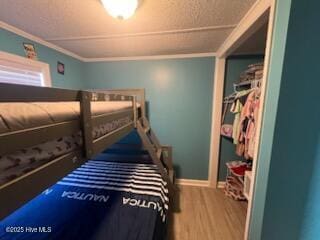 bedroom featuring wood-type flooring, ornamental molding, and a closet