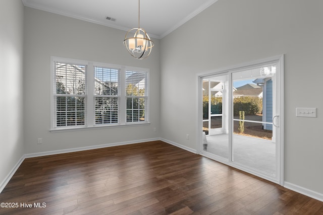 spare room with an inviting chandelier, a wealth of natural light, and dark wood-type flooring