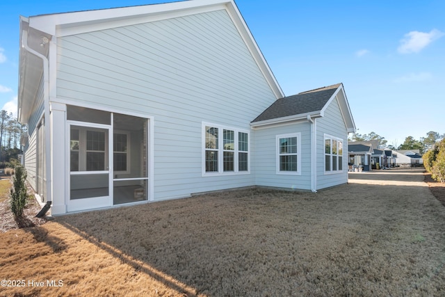 back of house with a sunroom and a lawn