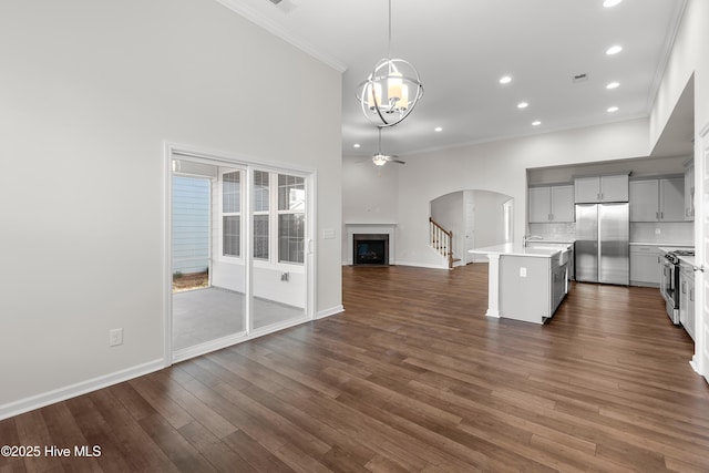 kitchen with stainless steel appliances, backsplash, hanging light fixtures, a kitchen island with sink, and crown molding