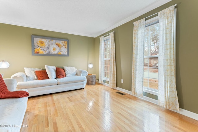 living room featuring a textured ceiling, hardwood / wood-style flooring, a wealth of natural light, and ornamental molding