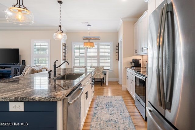 kitchen featuring stainless steel appliances, a kitchen island with sink, sink, and white cabinets