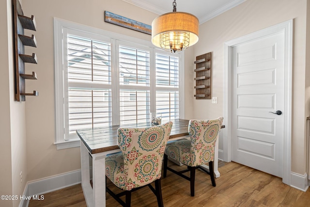 dining room with crown molding, a notable chandelier, hardwood / wood-style flooring, and a healthy amount of sunlight