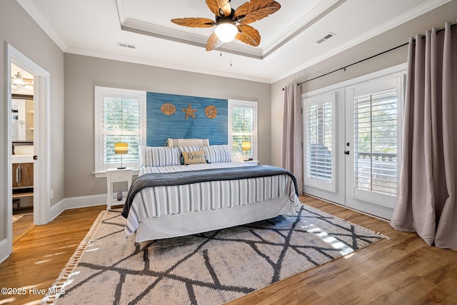 bedroom featuring ceiling fan, light hardwood / wood-style floors, ornamental molding, access to outside, and a raised ceiling