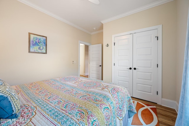 bedroom featuring hardwood / wood-style flooring, crown molding, and a closet