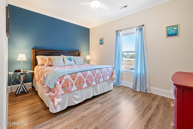 bedroom with hardwood / wood-style flooring, ornamental molding, and ceiling fan