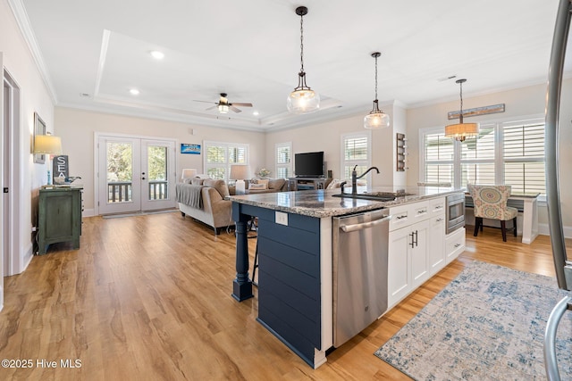 kitchen with appliances with stainless steel finishes, stone countertops, white cabinetry, a kitchen island with sink, and a tray ceiling