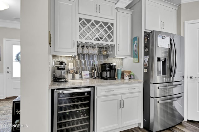 kitchen featuring stainless steel fridge, light stone counters, beverage cooler, crown molding, and white cabinetry