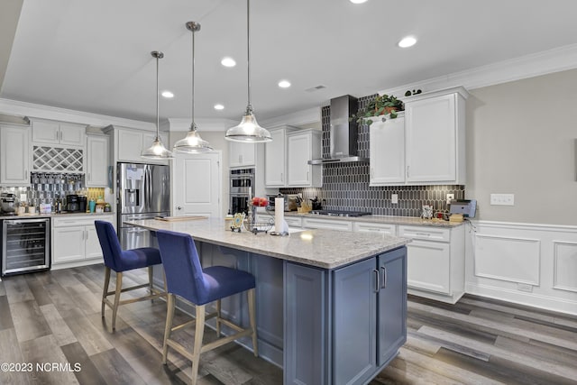 kitchen featuring wine cooler, wall chimney exhaust hood, pendant lighting, white cabinetry, and a kitchen island