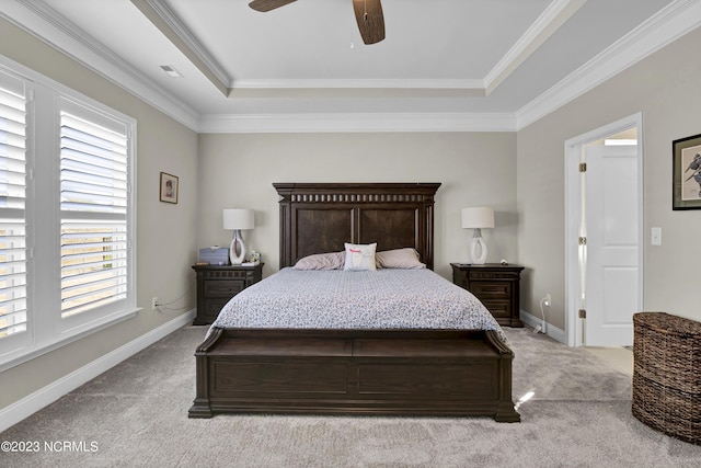 bedroom with a tray ceiling, multiple windows, ceiling fan, and light carpet