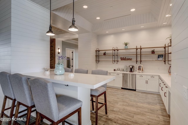 kitchen with kitchen peninsula, light wood-type flooring, white cabinetry, hanging light fixtures, and a breakfast bar area