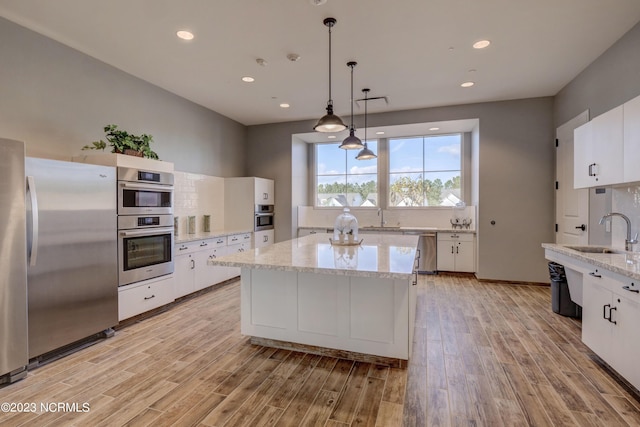 kitchen featuring white cabinets, decorative light fixtures, stainless steel appliances, and sink