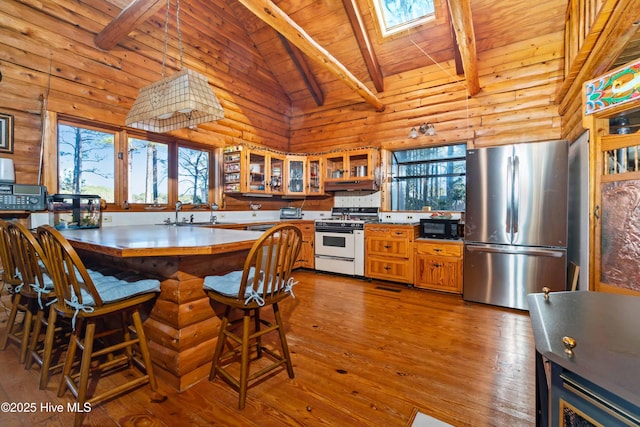 kitchen featuring stainless steel fridge, rustic walls, gas range gas stove, wooden ceiling, and beamed ceiling