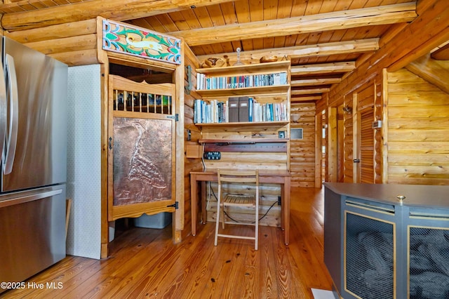 kitchen featuring beam ceiling, stainless steel refrigerator, rustic walls, hardwood / wood-style floors, and wood ceiling