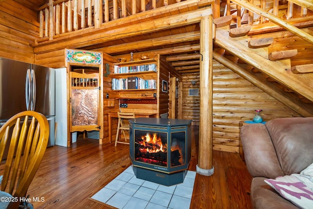 living room featuring log walls, beamed ceiling, hardwood / wood-style flooring, and wooden ceiling