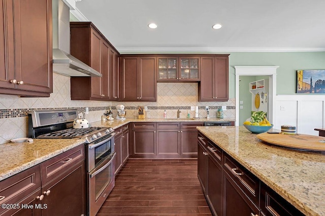 kitchen featuring light stone countertops, range with two ovens, wall chimney range hood, crown molding, and dark hardwood / wood-style flooring