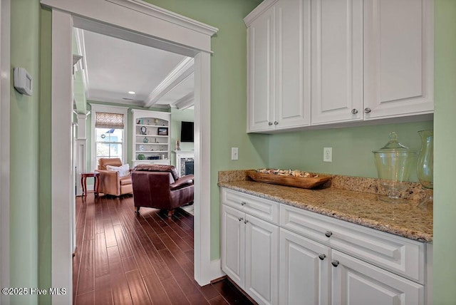 kitchen with white cabinets, light stone countertops, ornamental molding, and dark hardwood / wood-style floors