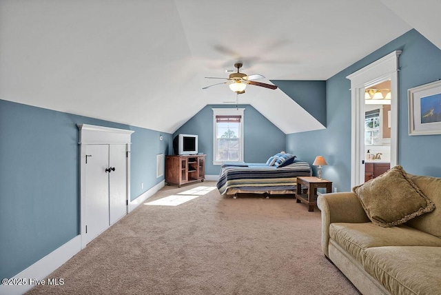 bedroom with connected bathroom, light carpet, ceiling fan, and vaulted ceiling