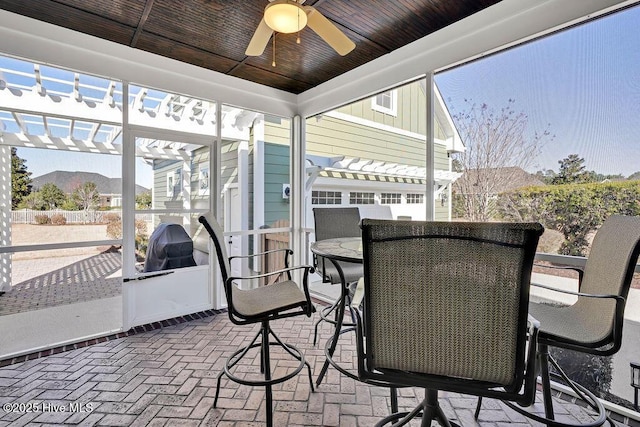 sunroom with a mountain view, ceiling fan, and wood ceiling