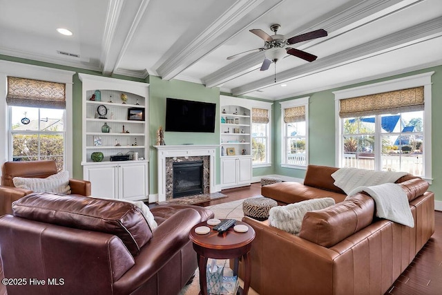 living room with ceiling fan, hardwood / wood-style flooring, a premium fireplace, crown molding, and beam ceiling