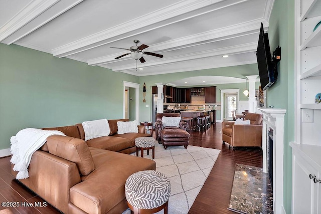 living room featuring light wood-type flooring, beam ceiling, crown molding, a fireplace, and ceiling fan