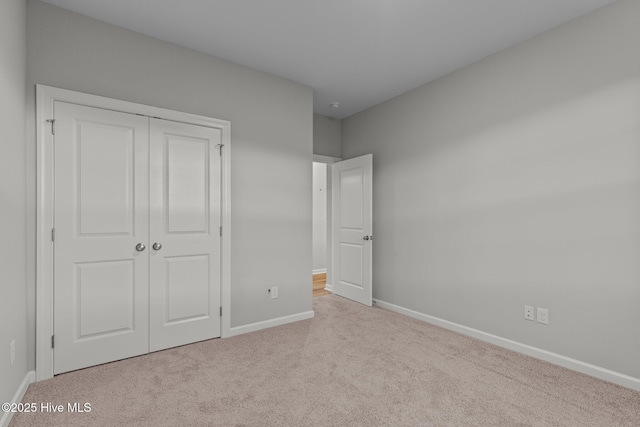 unfurnished bedroom featuring light colored carpet and a closet