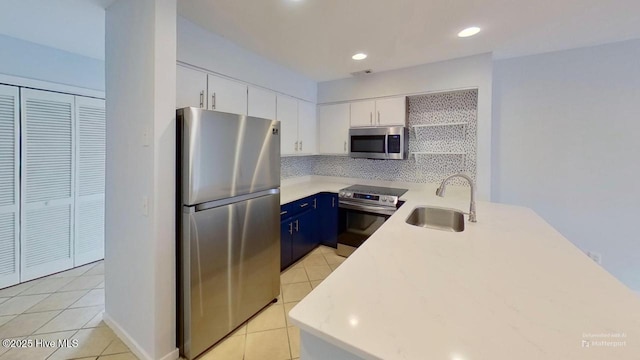 kitchen featuring tasteful backsplash, stainless steel appliances, blue cabinets, sink, and white cabinets