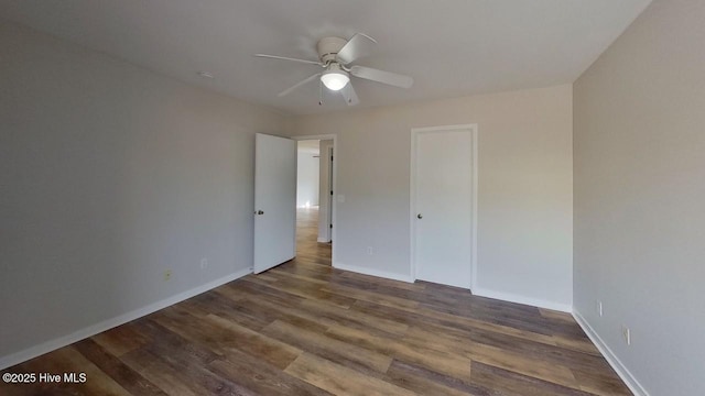 unfurnished bedroom featuring ceiling fan, dark hardwood / wood-style flooring, and a closet