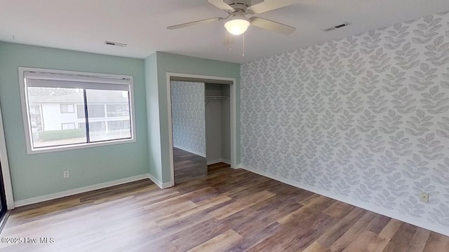 unfurnished bedroom with hardwood / wood-style flooring, ceiling fan, and a closet