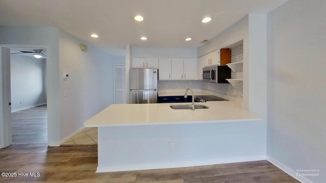 kitchen with kitchen peninsula, white cabinetry, stainless steel appliances, and tasteful backsplash