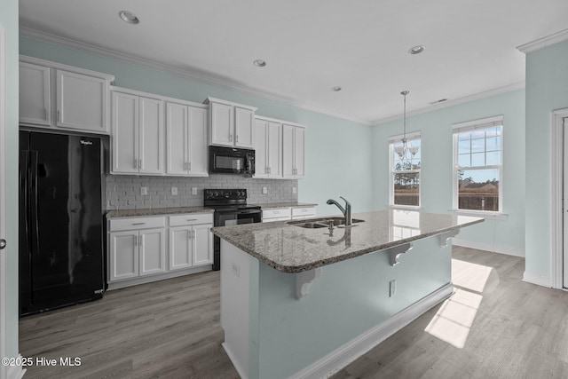 kitchen featuring black appliances, white cabinets, sink, and an island with sink