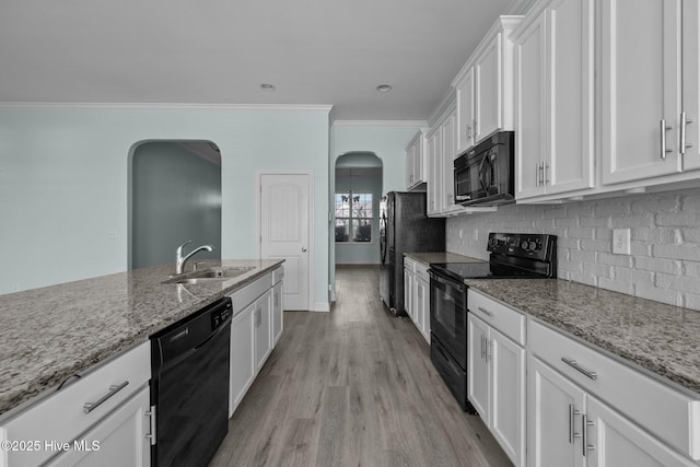 kitchen featuring light stone counters, ornamental molding, sink, black appliances, and white cabinets